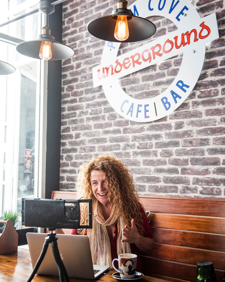 Lisa Monks recording social media content with her phone rig and laptop at the Underground Café in Palm Cove